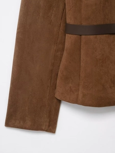 Détail de la veste en daim marron avec ceinture en cuir foncé et texture raffinée