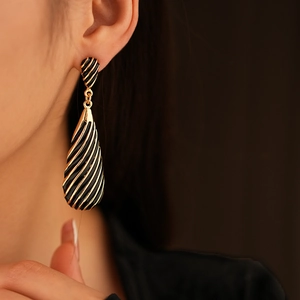 Gros plan de boucles d'oreilles vintage en goutte d'eau à rayures noires et dorées