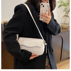 Chic white square crossbody bag with gold hardware shown on a model in a modern interior