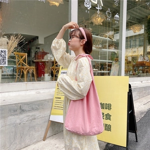 Pink canvas shoulder bag for women shown in a casual outdoor lifestyle setting