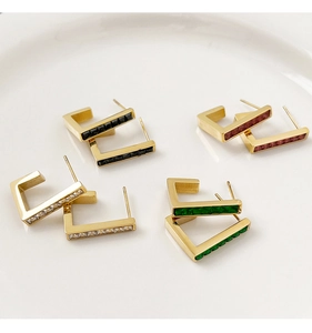 Detailed view of four pairs of golden U-shaped geometric earrings with colorful crystals