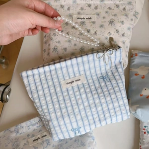 Detail of blue floral cotton bag with elegant pearl handle and silver bow pendant charm