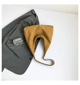 Minimalist ginger yellow suede hobo bag shown styled with a grey blazer and glass decor