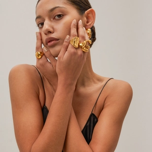 Set elegante di anelli e orecchini a goccia irregolari in oro indossati da una modella