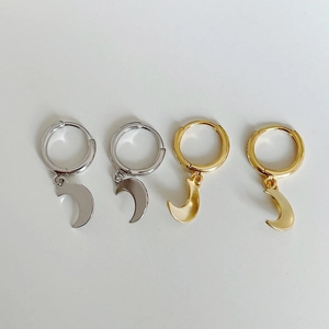 Detailed view of gold and silver sterling silver moon charm hoop earrings on white background