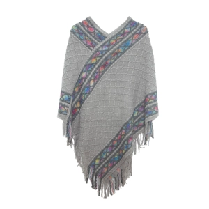 Detailed close-up of grey knitted poncho featuring colorful geometric trim and fringe tassels