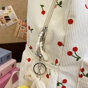 Detail of corduroy backpack showing cherry embroidery and smooth white zipper closure