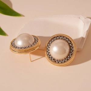 Detailed close-up of retro pearl earrings with silver chain trim and golden gear edges