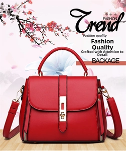 Detail of red leather crossbody tote with gold hardware lock and round top handles
