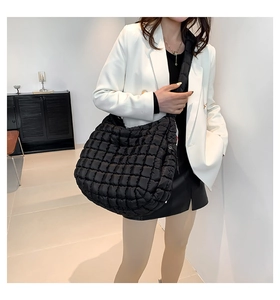 Detail of a large black quilted cloud bag showing the puffy texture and square stitching
