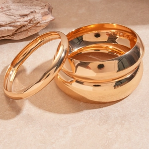 Detailed close-up of polished gold geometric bangles with a premium mirror finish