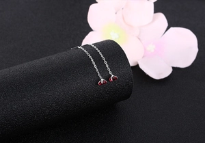 Detailed view of S925 silver threader earrings with red zircon drops on black display