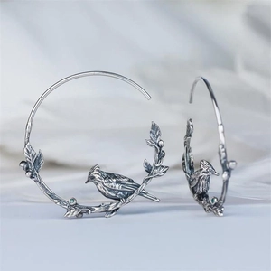 Vintage silver bird hoop earrings with green gemstone leaves and intricate branch details