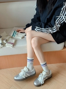 Detail of white cotton athletic crew socks with blue stripes and Smile embroidery on model