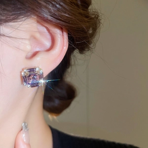 Close-up of luxury purple emerald cut stud earring with sparkling halo crystals