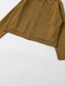 Dettaglio della giacca in maglia ocra con cerniera in metallo e due tasche applicate