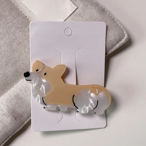 Detail of cute Corgi hair clip made of marbled acetate on a white jewelry display card