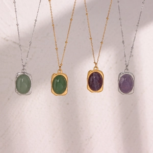 Detail view of oval gemstone pendants in green and purple on gold and silver chains