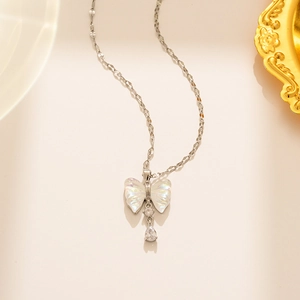 Detailed view of silver bow necklace with iridescent charm and clear crystal drop