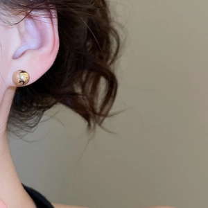 Close-up of elegant gold ball stud earrings worn by a model for a classic minimalist look