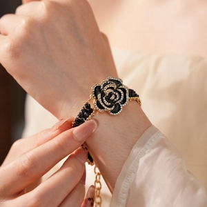 Close-up of elegant black rose bracelet with gold edging and crystals on wrist