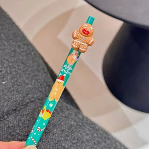 Close-up of green Christmas gel pen with gingerbread man topper and festive art patterns