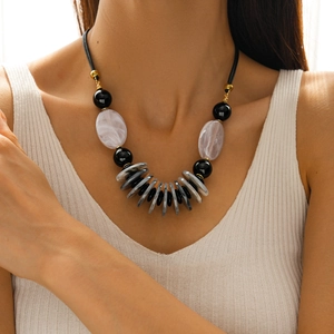 Detail of layered acrylic oval pendant necklace with faux leather cord and gold spacers