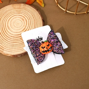 Detail of Halloween hair clip with pumpkin charm and glitter bow on a wooden base