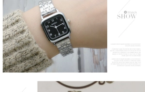 Detail of silver stainless steel strap and square black dial watch on woman's wrist
