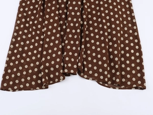 Close-up of brown pleated fabric with white polka dots showing soft texture and pattern
