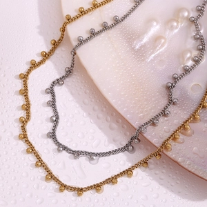 Macro shot of 18K gold and silver beaded necklaces on a seashell with water drops
