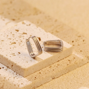 Macro view of geometric S925 sterling silver earrings on textured marble surface