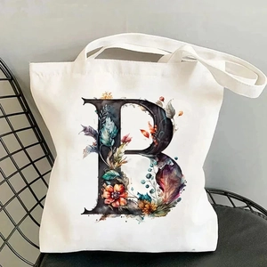 Detailed view of canvas tote bag featuring floral alphabet B print on a metal chair