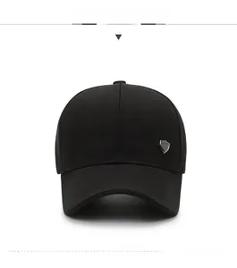 Detail of a black baseball cap with silver metal shield logo and reinforced stitching