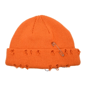 Close-up of orange distressed knit beanie with metal safety pin and ring details