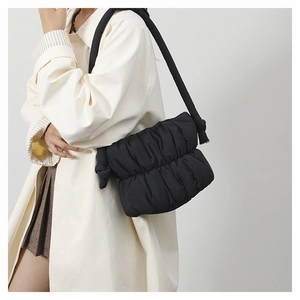 Detail of black pleated puffer bucket bag featuring a unique knotted shoulder strap design