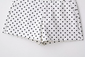 Dettaglio dei pantaloncini bianchi in cotone a pois neri con passanti e trama del tessuto
