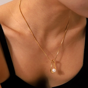 Golden necklace with hollow teardrop pendant and white pearl shown on female model