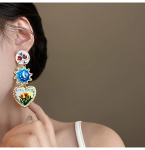 Detailed shot of multi-layer colorful enamel earrings with sun and heart-shaped charms
