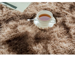 Close-up of soft brown plush rug texture with a magazine and tea for home comfort