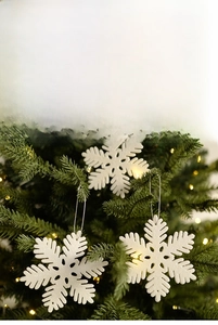 Close-up of white glittery snowflake ornaments with silver strings on a Christmas tree