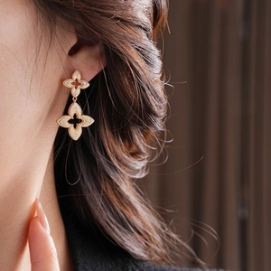 Detailed close-up of double-layer hollow four-petal flower earrings in gold finish
