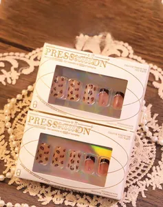 Detailed view of leopard print press-on nails set with pearls in luxury gift packaging