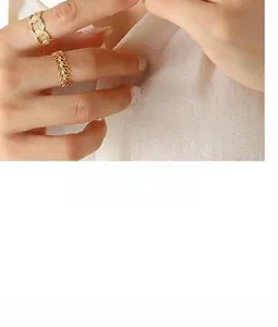 Détail de la bague à maillons dorés et anneau texturé feuille portés aux doigts