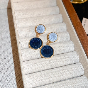 Detail of blue enamel butterfly floral earrings with golden edges on beige jewelry tray