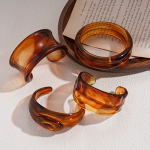 Vintage amber resin bangles with tortoiseshell patterns displayed on a rustic wooden tray
