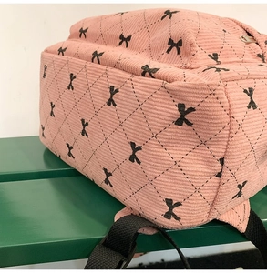 Close-up of pink corduroy backpack featuring diamond quilted stitching and bow embroidery
