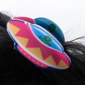 Close-up of a cartoon alien UFO hair claw clip on black hair with vibrant colors