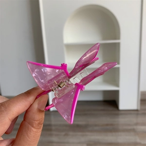 Detail of pink pearlescent butterfly hair claw clip with transparent spring structure