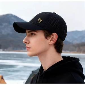 Detail of breathable laser-cut holes and gold metal logo on a black outdoor baseball cap